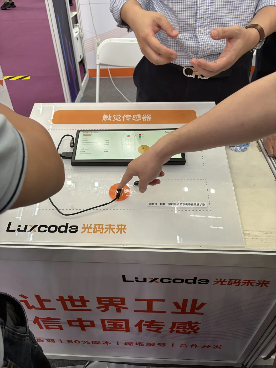 Testing a tactile sensor at a supplier booth, live readout on screen